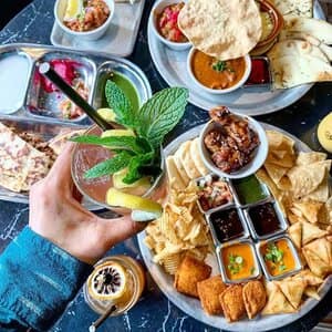 Indian Fast Casual Restaurant Hand holding drink and platters of food at franchisee location