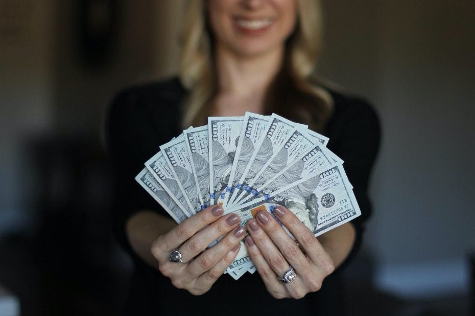 woman holding an handful of cash to show earning a 10 ROI