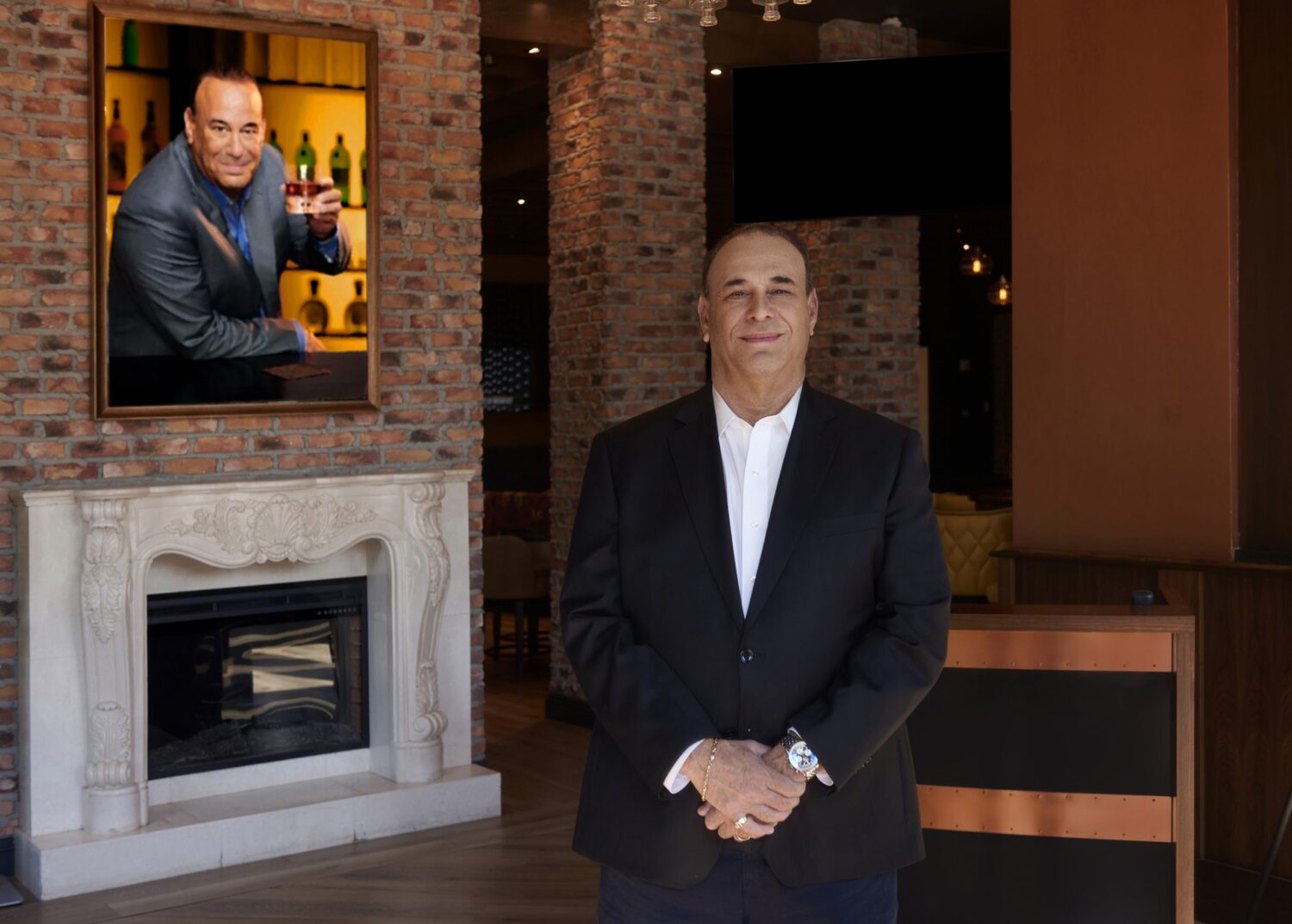 Jon Taffer posing in front of a brick wall and white fireplace