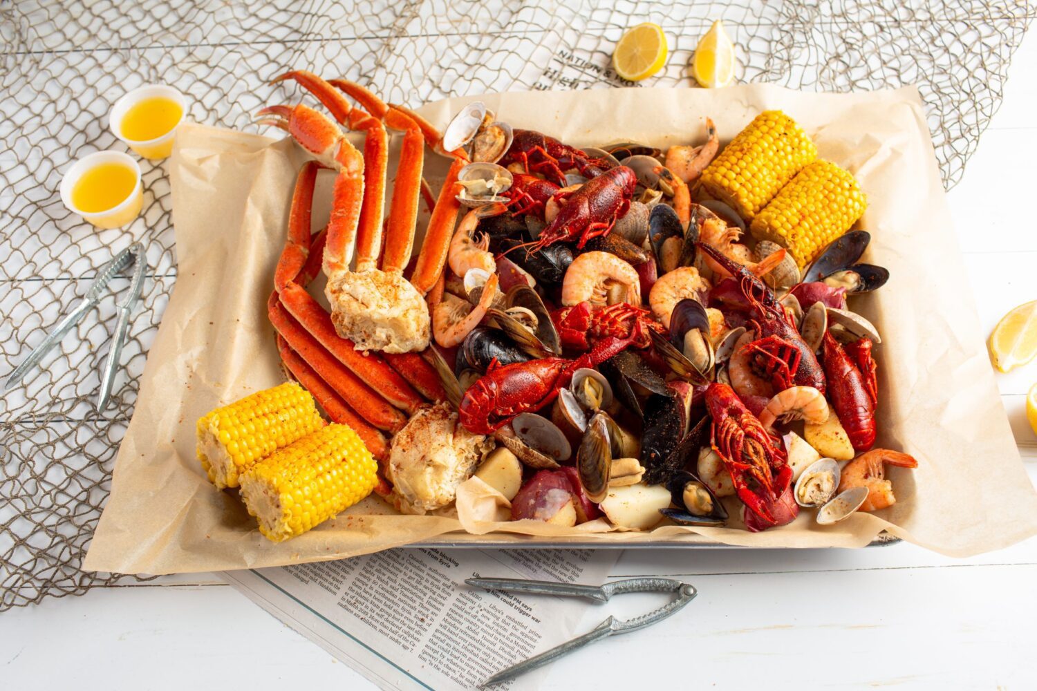 Seafood boil containing crab legs, shrimp, clams, corn on the cob and lemon