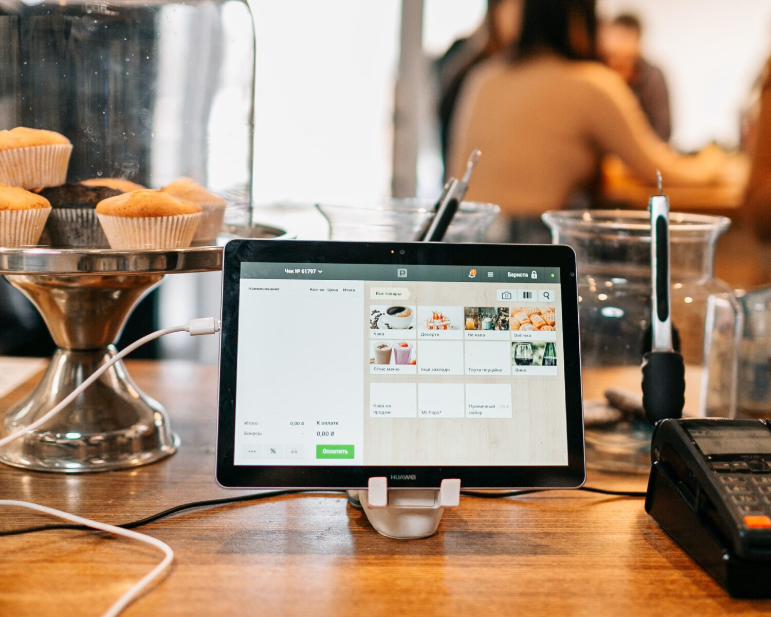 restaurant pos system shown on a checkout counter, people at a table in the background