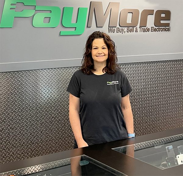 A female PayMore employee wearing black shirt smiling for camera 