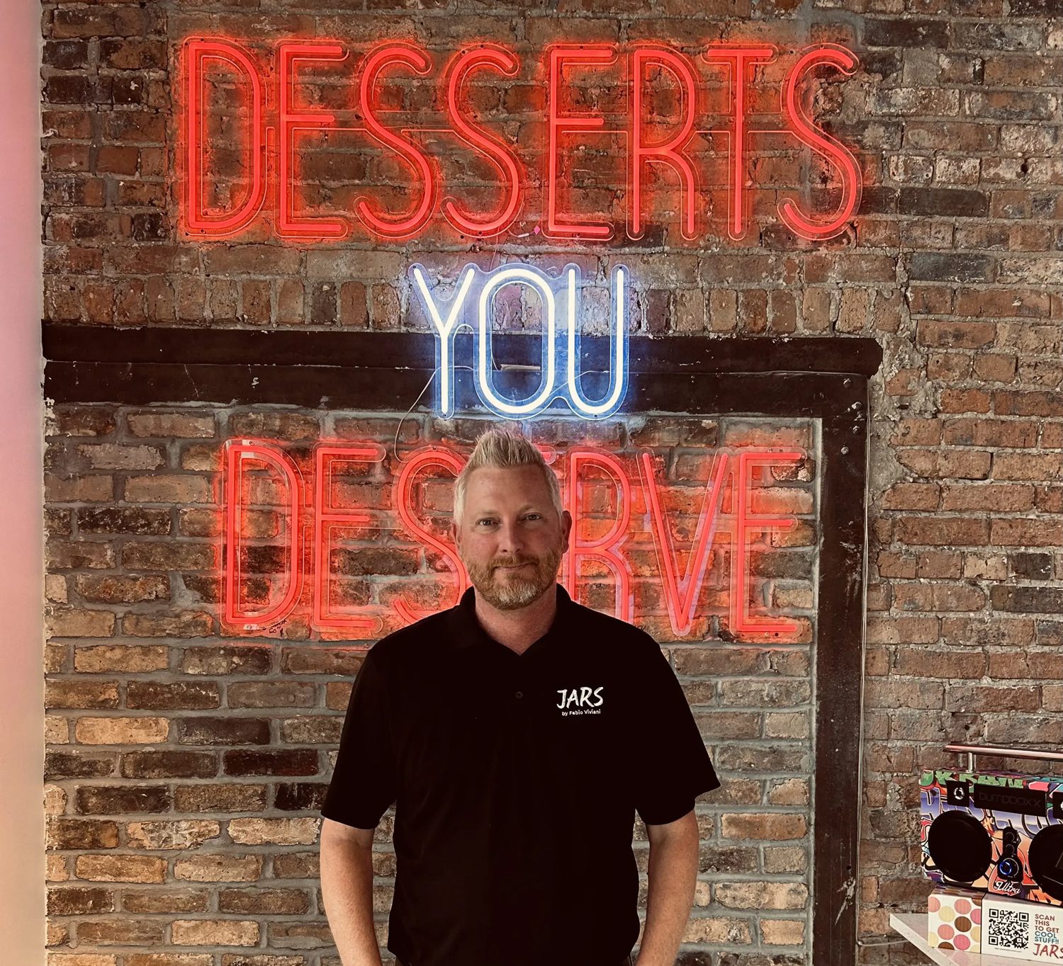 Chris Carlton standing in front of a sign reading desserts you deserve