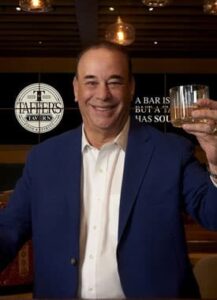 Bar Rescue Star Jon Taffer standing in front of a Taffer's Tavern sign